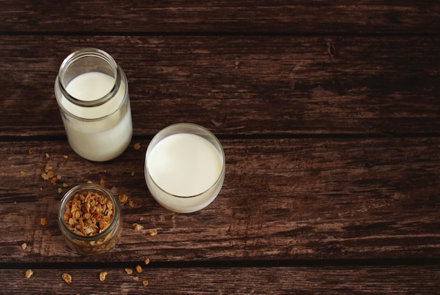 Fermented milk product kefir in a glass jar with granola on a beige background