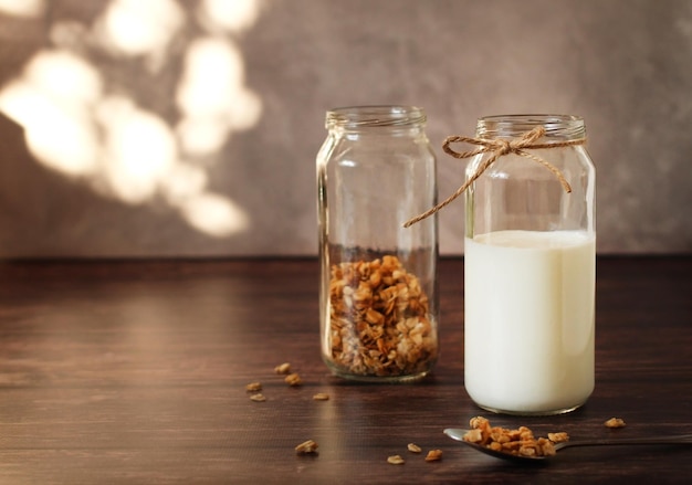 Fermented milk product kefir in a glass jar with granola on a beige background