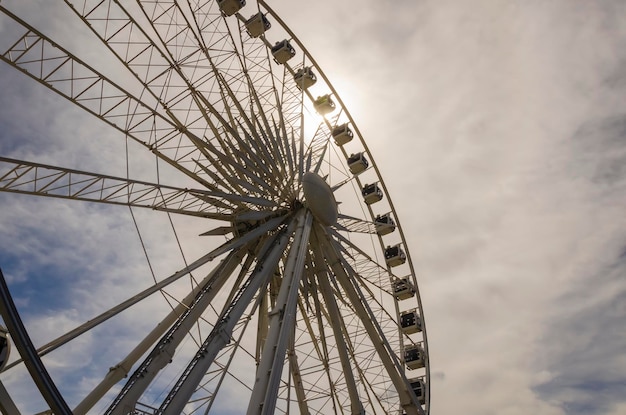 Ferris wheel in Gdansk against blue sky and sun.