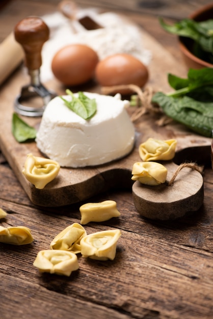 Fesh tortellini ravioli on wooden rustic table with spinach and ricotta