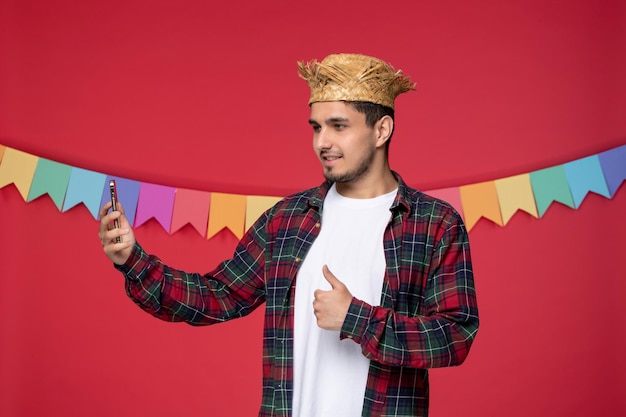 Festa junina smiling cute guy wearing straw hat celebrating brazilian festival taking selfie