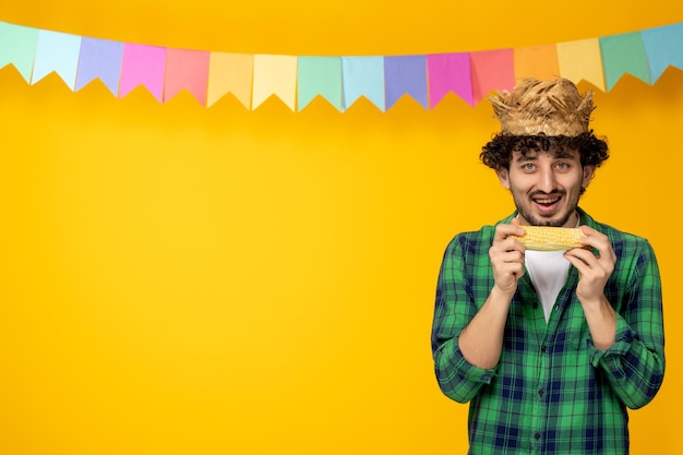 Festa junina young cute guy in straw hat and colorful flags brazilian festival eating corn