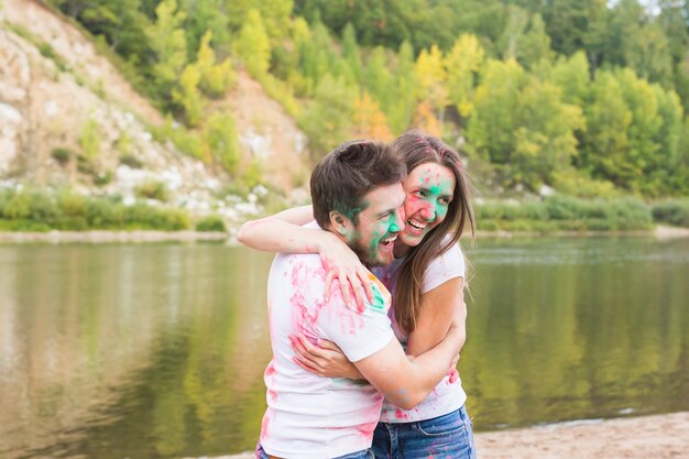 Festival holi, holidays, tourism and nature concept - Portrait of woman and man covered multi-colored dust.