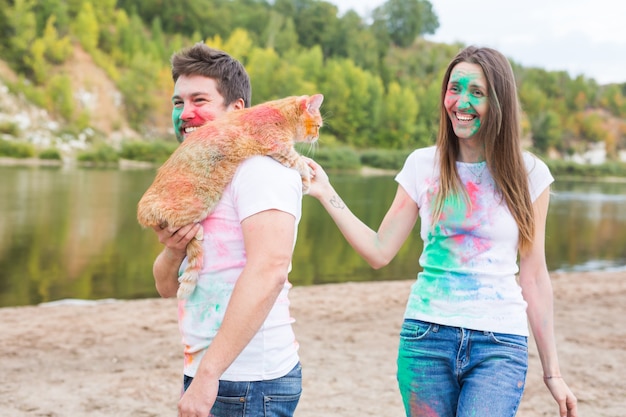 Festival holi , tourism and nature concept - Portrait of woman and man with cat covered multi-colored dust.