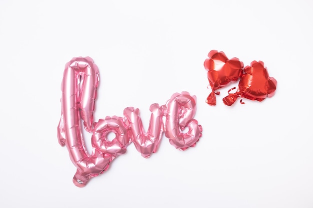 Festive background for Valentine's Day from foil balloons shape heart and love word on white background