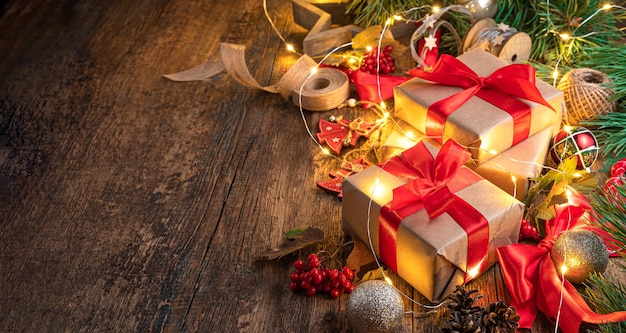 Festive background with gifts Christmas tree toys and a burning garland on a wooden table