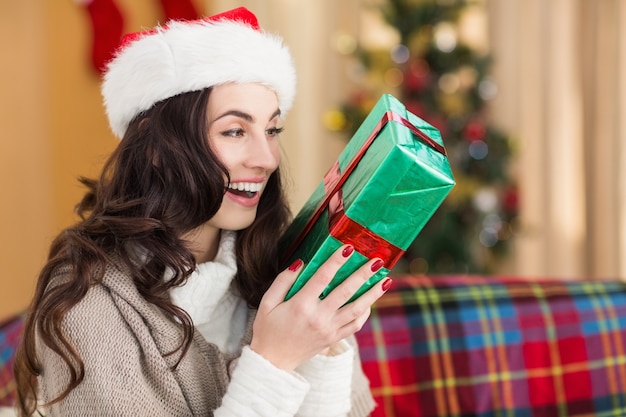 Festive brunette holding gift at christmas