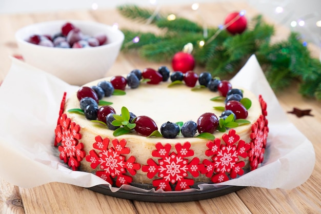 Festive cake for Christmas holidays Recipe of cheesecake with blueberry and cranberry in pastry snowflakes with fir branches in Christmas lights Original treats for winter holidays entertainment