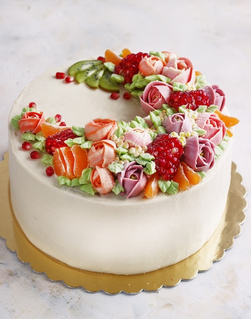 Festive cake with cream flowers and fruits on a light