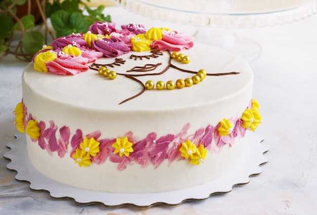 Festive cake with cream flowers and a girl face on a light background