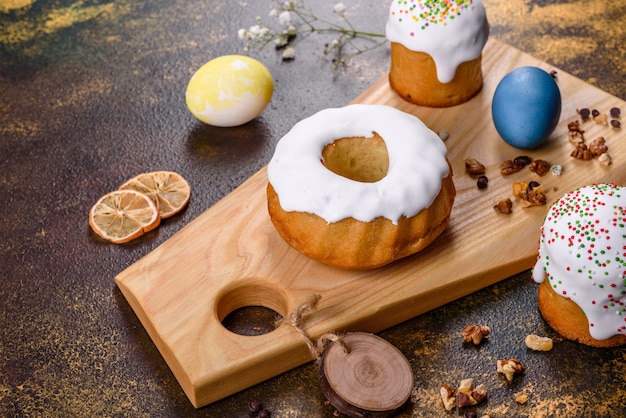 Festive cakes with white glaze, nuts and raisins with Easter eggs on the festive table. Preparations for Easter