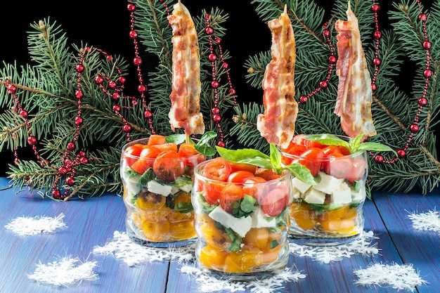 Festive caprese salad with fried bacon on skewers in glasses