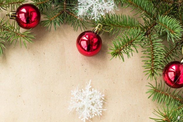 Festive christmas border with red balls on fir branches and snowflakes on rustic beige background