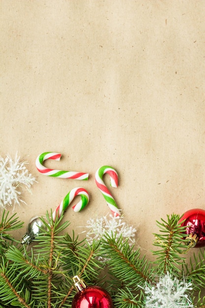 Festive christmas border with red and silver balls on fir branches and snowflakes on rustic beige background