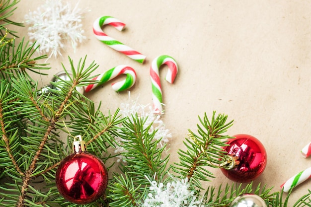 Festive christmas border with red and silver balls on fir branches and snowflakes on rustic beige background