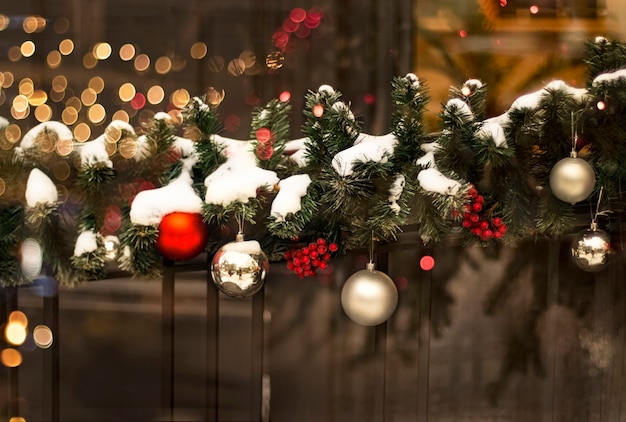 Festive Christmas decoration of fir branches with balls berries garland in the evening lights