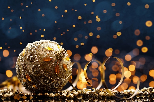 Festive Christmas gold ball with decoration on dark blue