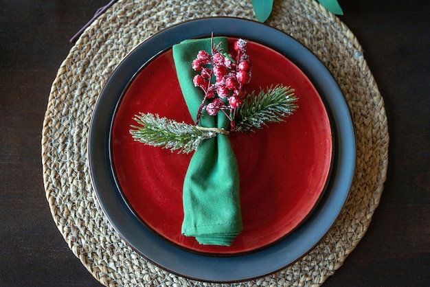 Festive christmas table setting with green napkin decorated with a sprig with berries and fir branch