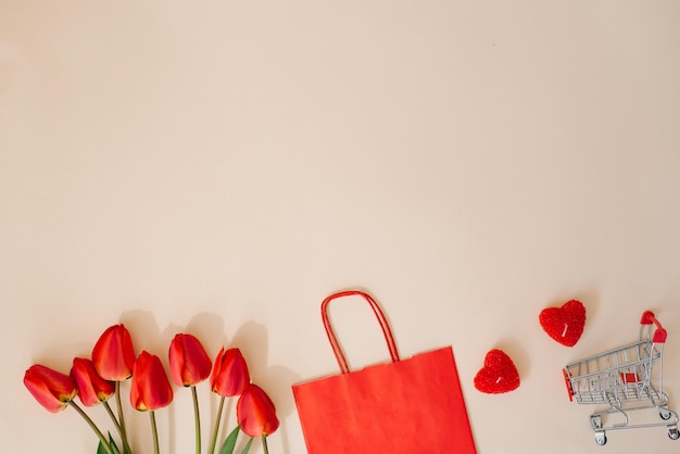 Festive composition gift paper red bag hearts a bouquet of tulip flowers with a shopping basket