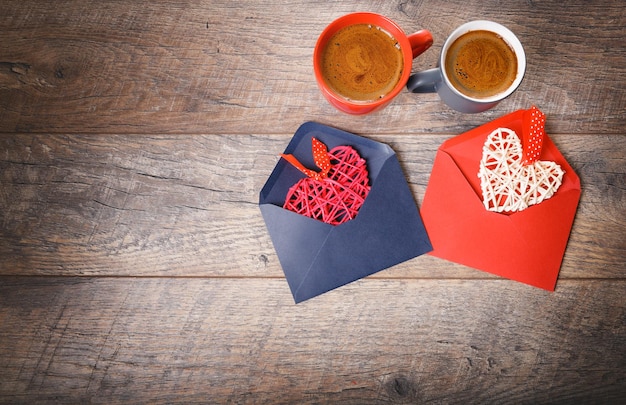 Festive composition on rustic wood table red and gray mug with marshmallows or cocoa hearts in envelopes dried rose flowers