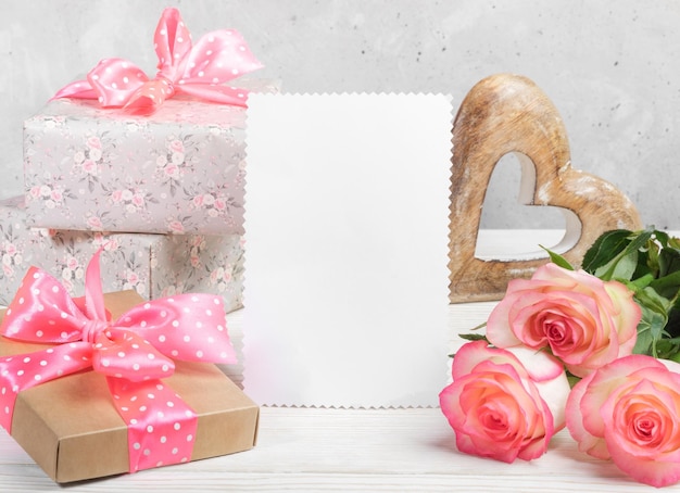 Festive composition with gift boxes peach color roses wooden heart empty white blank for text