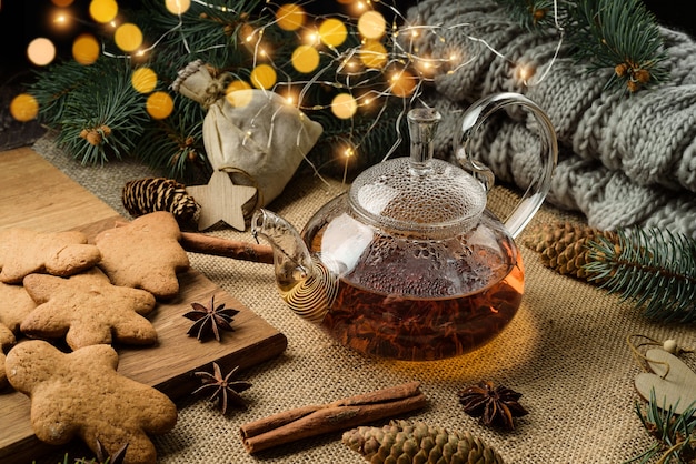 Festive composition with gingerbread cookies and glass teapot in Christmas decor.