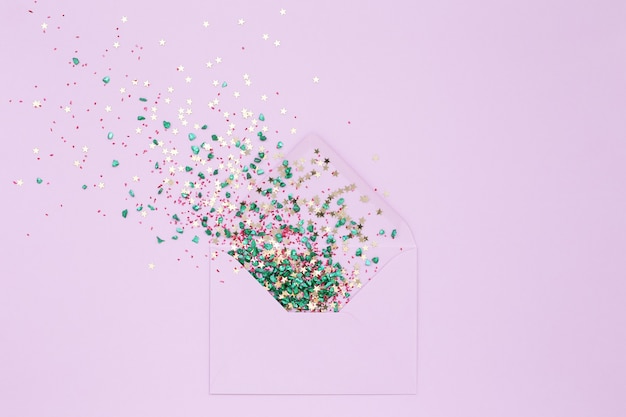 Festive confetti explosion from envelope on lilac background