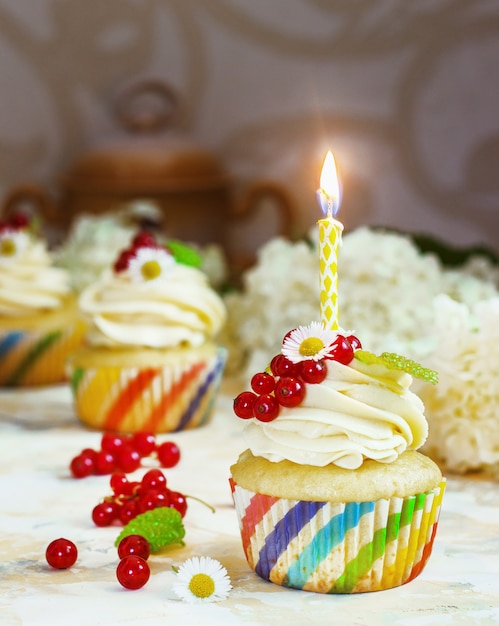 festive cupcake with cream and berries and a candle