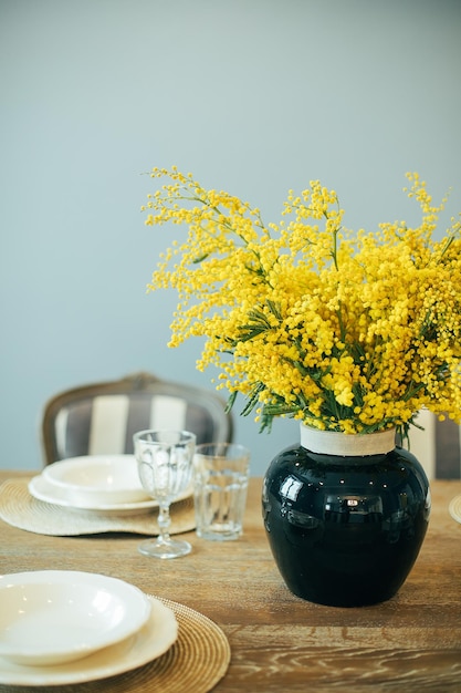 Festive Easter table setting Branches of mimosa in vase Home interior