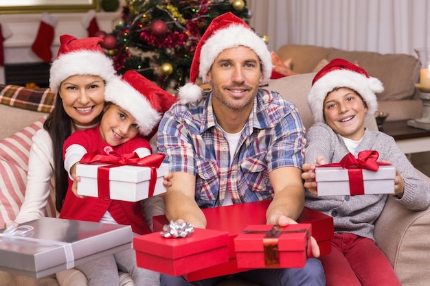 Festive family on the couch offering gifts 