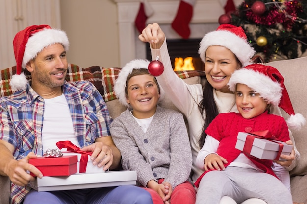 Festive family wearing santa hat on the couch at home in the living room