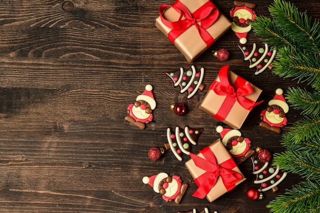 Festive gift boxes Christmas on wooden background. chocolate candies in the shape of a Christmas tree and Santa Claus.