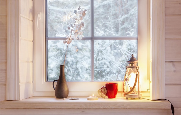 Festive lantern red mug and heart on a wooden window sill in winter indoors