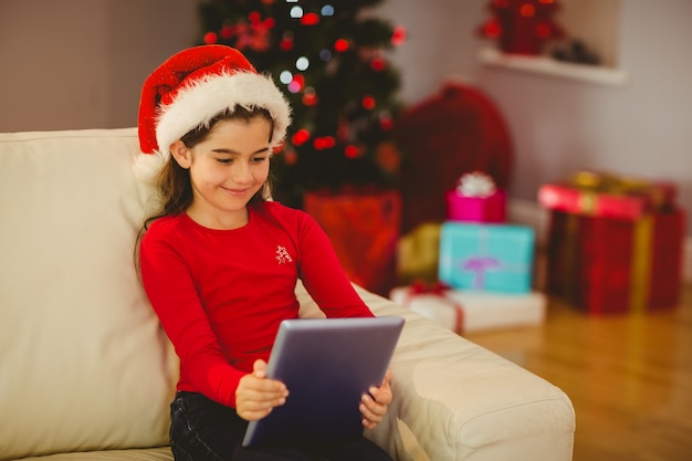 Festive little girl using tablet pc on couch