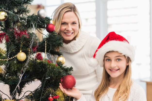 Festive mother and daughter decorating christmas tree