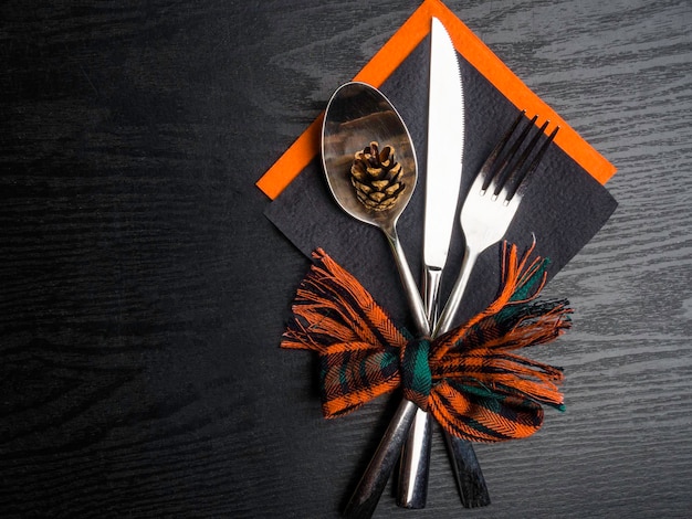 Festive place setting for christmas or new year dinner Beautiful cutlery and christmas decoration on the red and black napkin and vintage wooden background Top view copy space