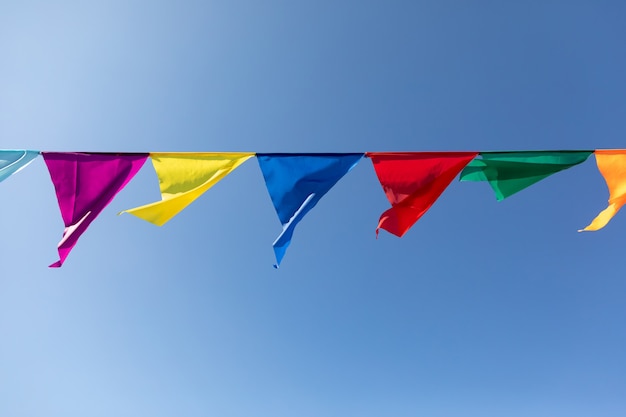 Festive ribbon made of multicolored triangles on the background of the blue sky. Celebration Party.