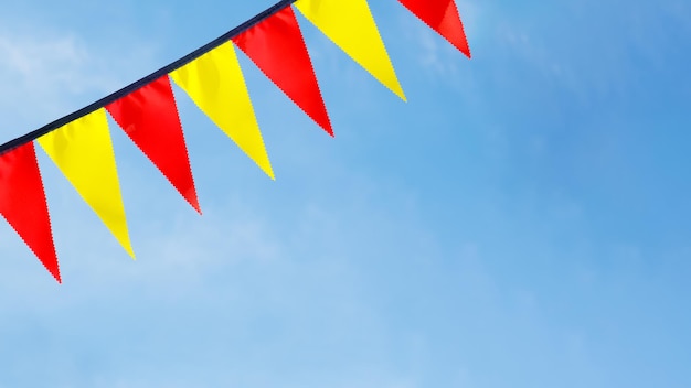 Festive ribbon of red and yellow triangle flags on the white clouds and blue sky background