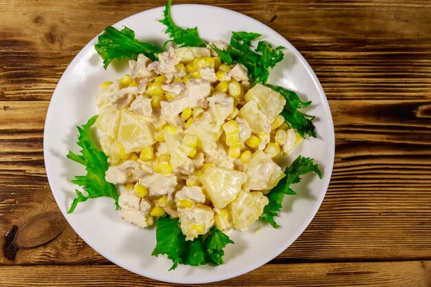 Festive salad with chicken breast sweet corn canned pineapple and mayonnaise on wooden table