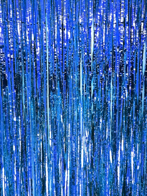 Photo festive shiny tinsel fringe, blue background with selective focus.