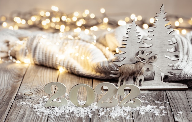 Festive still life with decorative number of the coming year on a wooden surface with decorative elements against a blurred background.