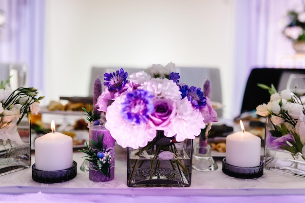 Festive table decorated with composition of violet purple pink flowers and greenery candles in the banquet hall Table newlyweds in the banquet area on wedding party