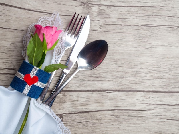 Festive table setting for Valentine's Day with cutlery roses and hearts on white wooden table Space for text