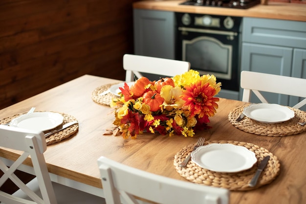 Festive wooden table with wicker napkins, flowers, white plates and cutlery in dining room