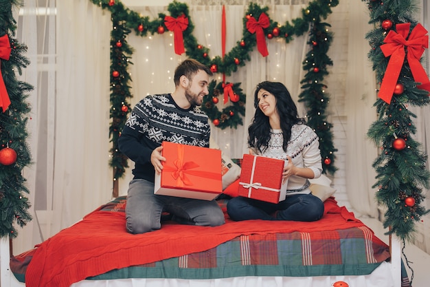 Festive young couple exchanging presents on christmas background