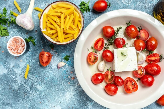 Feta bake pasta recipe made of cherry tomatoes, feta cheese, garlic and herbs in a casserole dish. 