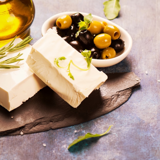 Photo feta cheese with fresh herbs, black and green olives