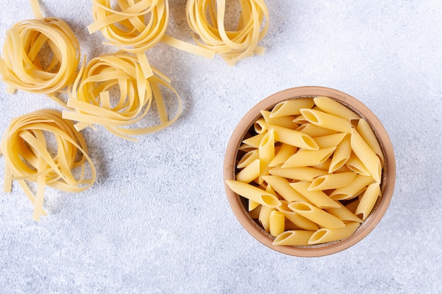 Fettuccine and penne pasta on white plaster