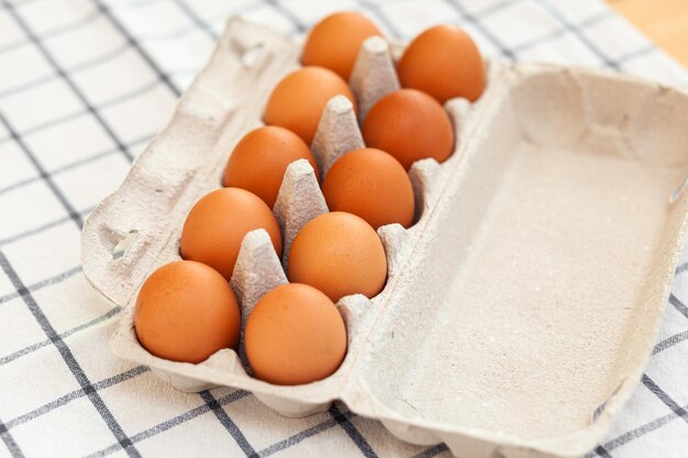 A few brown eggs among the cells of a large cardboard bag, a chicken egg as a valuable nutritious product, a tray for carrying and storing fragile eggs. A full package of eggs, an important food item