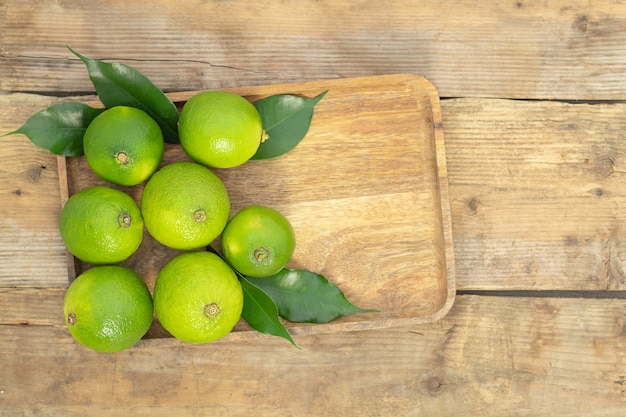 A few green limes on a tray on a wooden background  top view